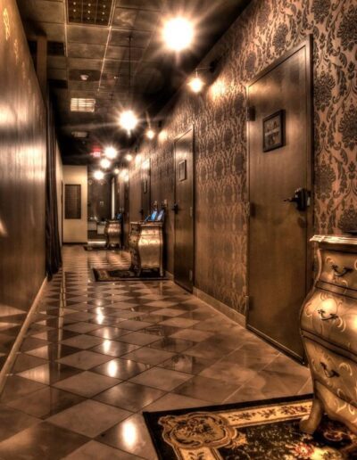 Elegant corridor with decorative wallpaper, checkered floor, and ornate furniture.