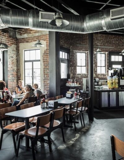 A group of patrons dining in an industrial-styled restaurant with exposed brick walls and ductwork.