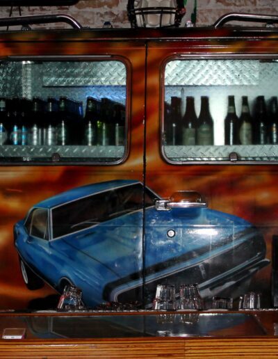 A bar designed to resemble the rear of a classic vehicle, complete with working tail lights and a custom paint job featuring automotive and model imagery.