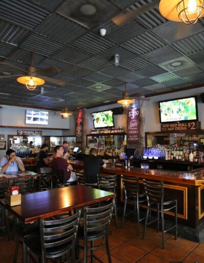 Interior of a casual bar with patrons seated and televisions displaying sports.