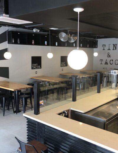 Interior of a modern taco restaurant with a black and white color scheme and pendant lighting.