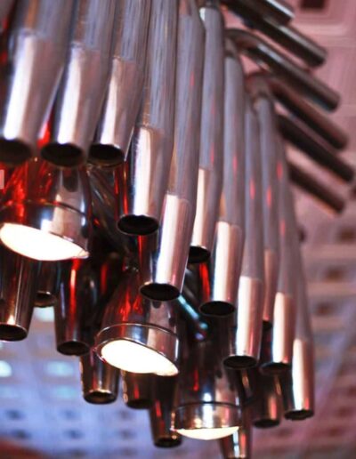 A cluster of cylindrical metallic pendant lights hanging from a ceiling.