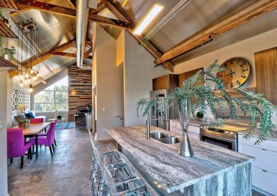 Modern kitchen with industrial design elements, featuring a large wooden island, stainless steel appliances, and exposed ceiling beams.