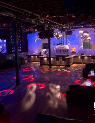 An empty nightclub interior with colorful lighting and a dance floor.